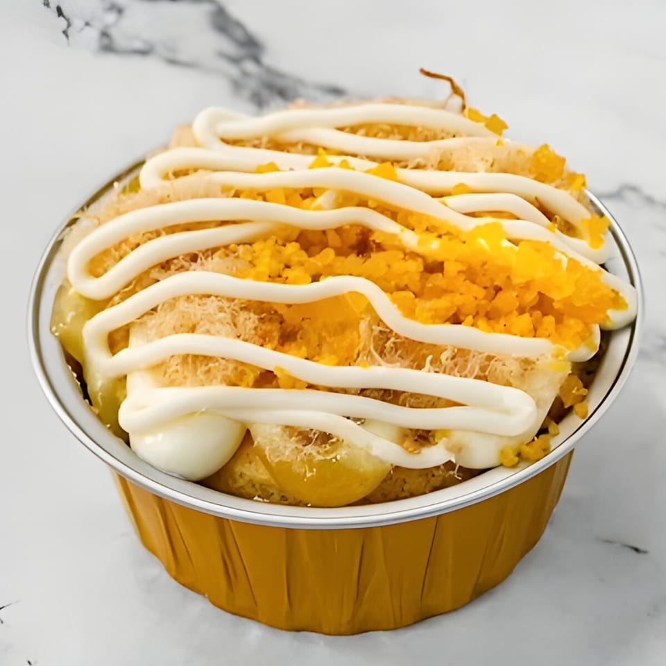 Mama Ha's Eatery Vietnamese dessert with mayonnaise, shredded pork, and orange topping in a gold cup.
